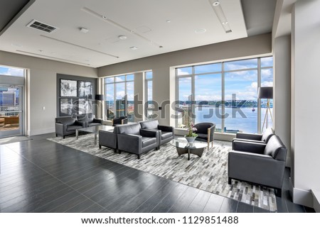 Modern interior design of living area with black leather armchairs and exit to luxurious terrace overlooking the Puget Sound. Northwest, USA