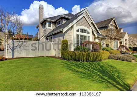 Classic American House With Fence And Green Grass During Spring.