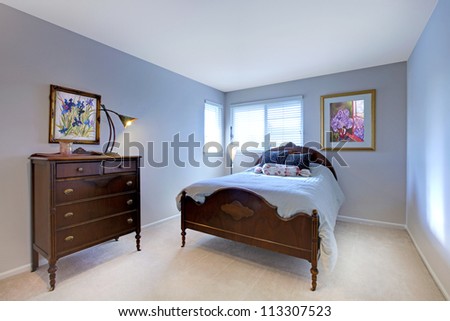 Blue bedroom with dark wood bed and dresser and beige carpet.