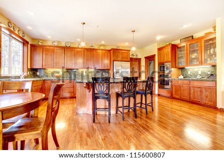 Luxury beautiful large cherry wood kitchen with green tile back splash and yellow walls.
