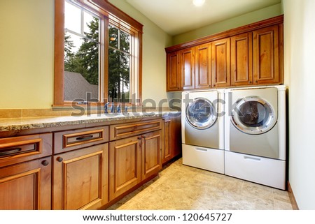 Luxury Laundry Room With Wood Cabinets And Tile Floor.