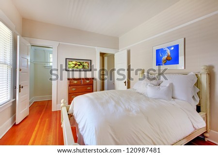 Bedroom with white bed and cherry hardwood floor.