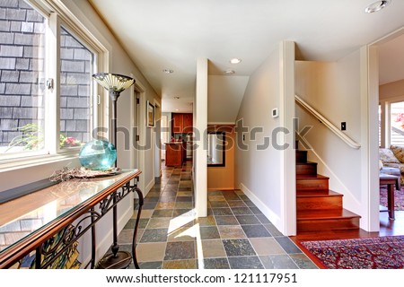 Home large hallway with stairs and window with table.