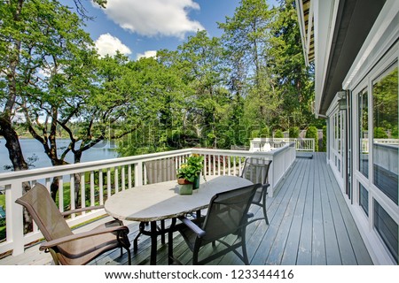 Large Long Balcony Home Exterior With Table And Chairs, Lake View.