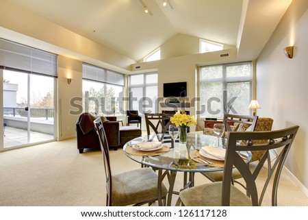 Large bright living and dining room with vaulted ceiling and TV.