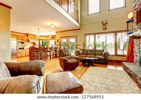 Living room with high ceiling, stone fireplace and leather sofa.