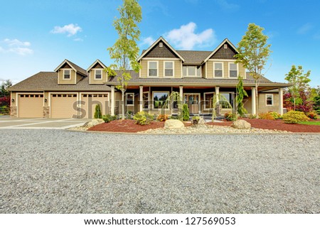 Large farm country house with gravel driveway and green landscape.