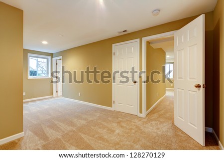 Empty new bedroom with many doors and beige carpet.