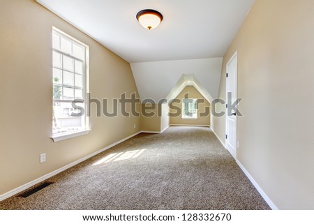 Empty new beige room with vaulted ceiling and two windows.