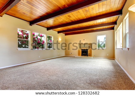 New large empty living room with wood ceiling and fireplace.