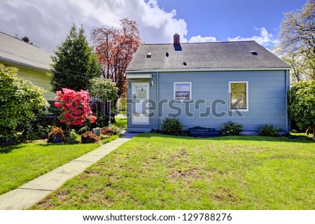 Blue small house with spring landscape from backyard with green grass. American house build in 1942.