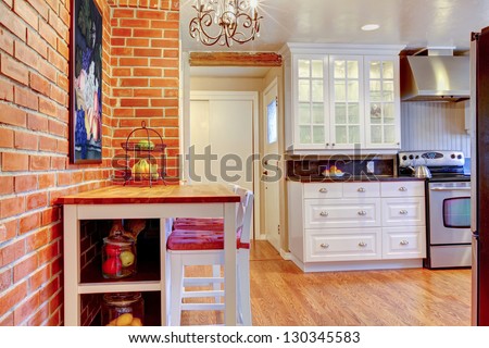 White Kitchen With Brick Wall, Hardwood And Stainless Steal Stove With Breakfast Table.