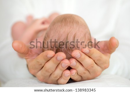 Adult Hands holding newborn baby with white background.