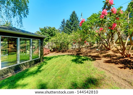 Garden studio house with windows and flowering bushes.