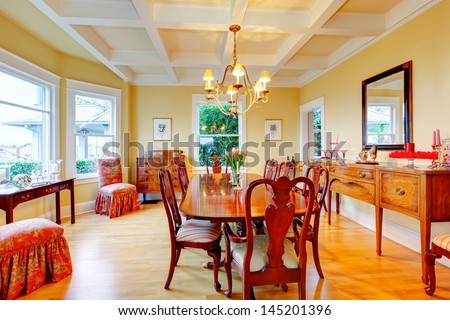 Golden bright yellow luxury dining room with elegant classic furniture and white wood ceiling.