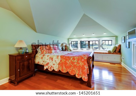 Green bedroom with vaulted ceiling, hardwood floor  and window bench.