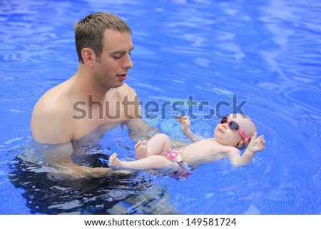 Tropical vacation with an infant. Small baby girl is swimming in the pool with daddy. Three months old baby who loves to swim.