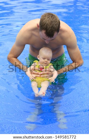 Tropical vacation with an infant. Small baby girl is swimming in the pool with daddy for the first time. Three months old baby.