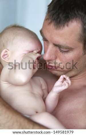Young father is holding very sleepy and tired baby girl.