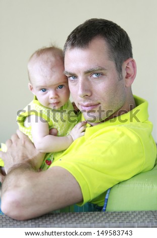 Father and little baby girl are playing together wearing neon green.