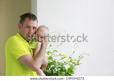Daddy\'s girl. Young father is holding baby girl. Both wearing neon green.