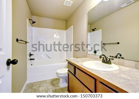 New home bathroom  interior with shower and bath combination, wood cabinet and toilet.