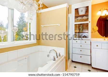 Bathroom with large white tub and storage cabinet.