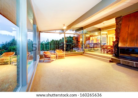 Huge almost empty living room with copper fireplace and glass window walls. Luxury real estate in Seattle.