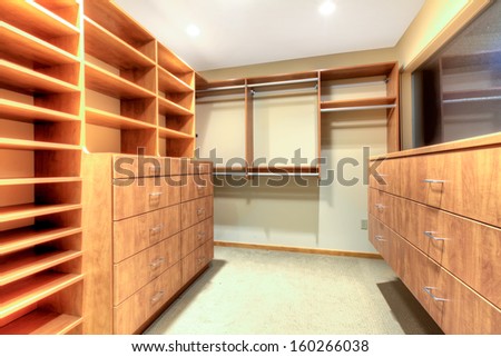 Luxury empty closet with wood build in shelves and cabinets.