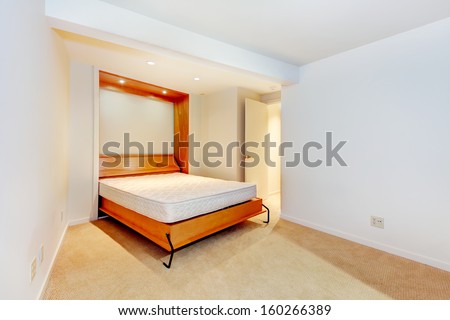 Modern empty bedroom with build in day bed and wood frame. Beige carpet. Luxury home interior, guest bedroom.