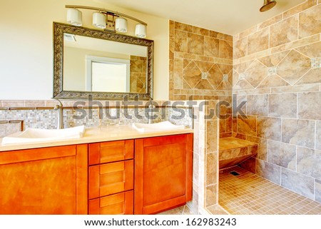 Renovated bathroom with wood cabinets, natural tiles and walk-in shower.