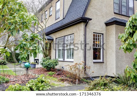 Cute old town home with grey brown stucco exterior. Early spring. American home exterior.