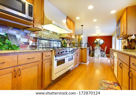Bright kitchen room with wooden cabinets and hardwood floor. Small dining area