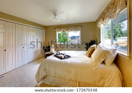 Light tones bedroom with a queen size bed, beige carpet floor, walk-in closet
