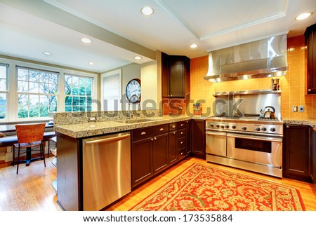 Bright kitchen and dining room with black wood cabinets and shiny steel appliances