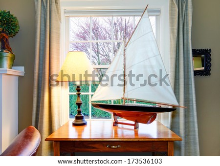 Classic living room with a wonderfully matched handicraft sailboat on rustic wooden table