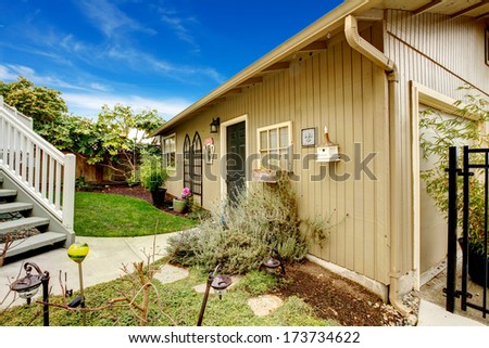 Spring backyard with flowerbed, trees and naturally matched wooden shed