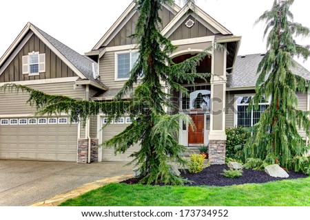 BIg siding house with porch columns stoned at base, tile roof and beautiful flower bed and trim