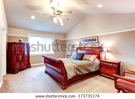 Beige bedroom with cathedral ceiling, carpet floor and great carved bed frame and storage cabinets