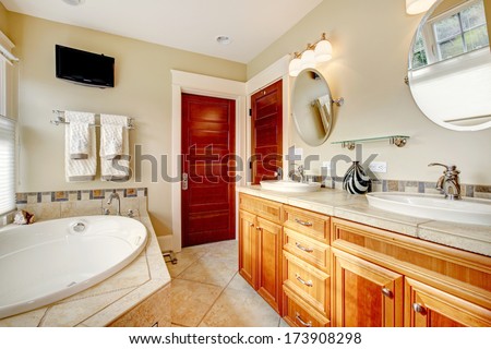Light tones bathroom with wood cabinets, tile floor, tv