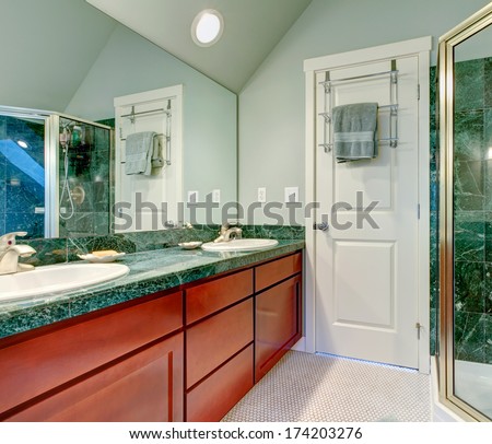 Light green bathroom with vaulted ceiling, tile floor and brown cabinets