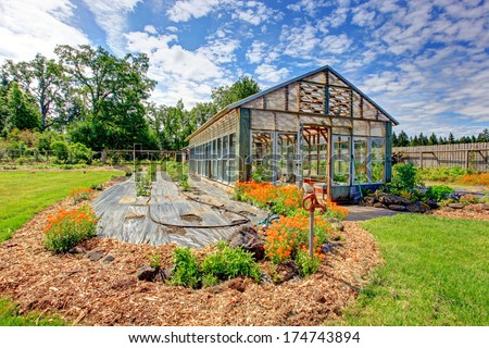 Fenced farm backyard with big green house