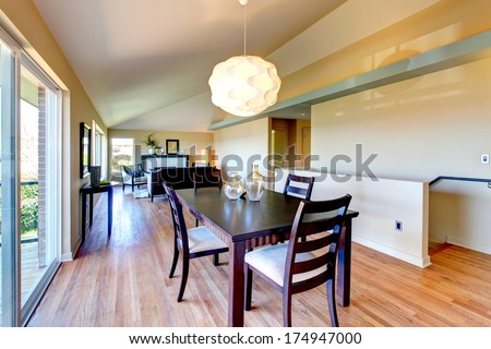 Open plan living room and dining area. Light tone vaulted ceiling perfectly matches hardwood floor and wood dining table set