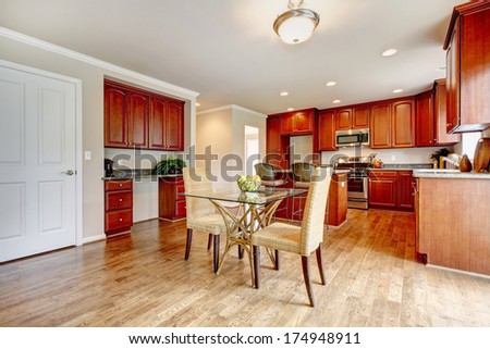 Hardwood floor big kitchen room with cherry wood cabinets and light tones dining table set