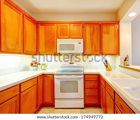 Small kitchen room with wood storage combination, white stove and microwave