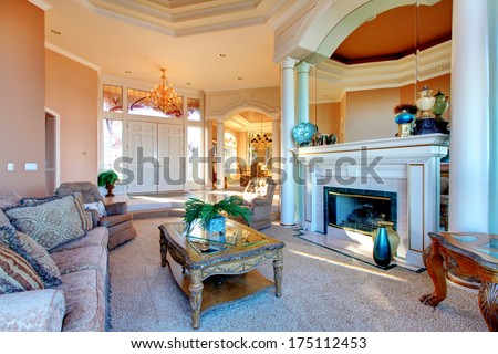 Large rich living room with fireplace accomplished with rustic and antique furniture, colomns and great designed ceiling
