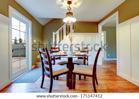 Bright small dining area with walkout deck. Hardwood floor, white stairs and olive wall complete the refreshing look of the interior