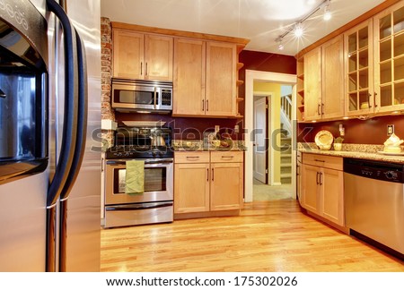 Impressive kitchen with burgundy backsplash, brick wall, wood storage combination and hardwood floor