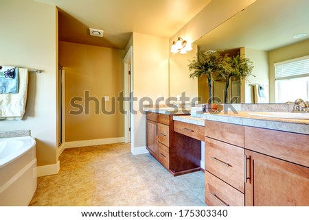 Ivory bathroom with wood storage cabinets, beige tile floor. Decorated with ceramic pot with small tree