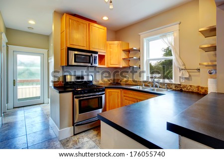 Modern Kitchen With Wood Storage, Black Counter Tops, Steel Appliances And Concrete Floor